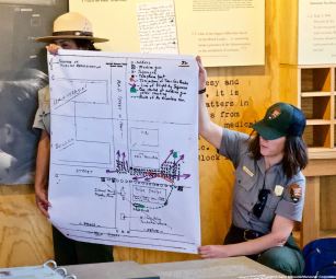 Manzanar NHS Superintendent Bernadette Johnson (left) and Ranger Rose Masters (right) are shown here with a map/chart of what may have occurred during the Manzanar “Riot,” December 5-6, 1942.